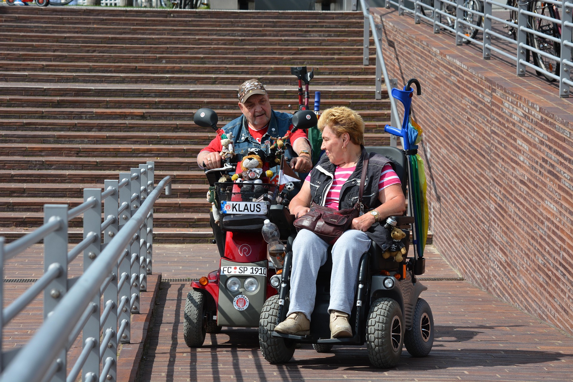 Two friends on wheelchair making use of an accessible staircase in a building.