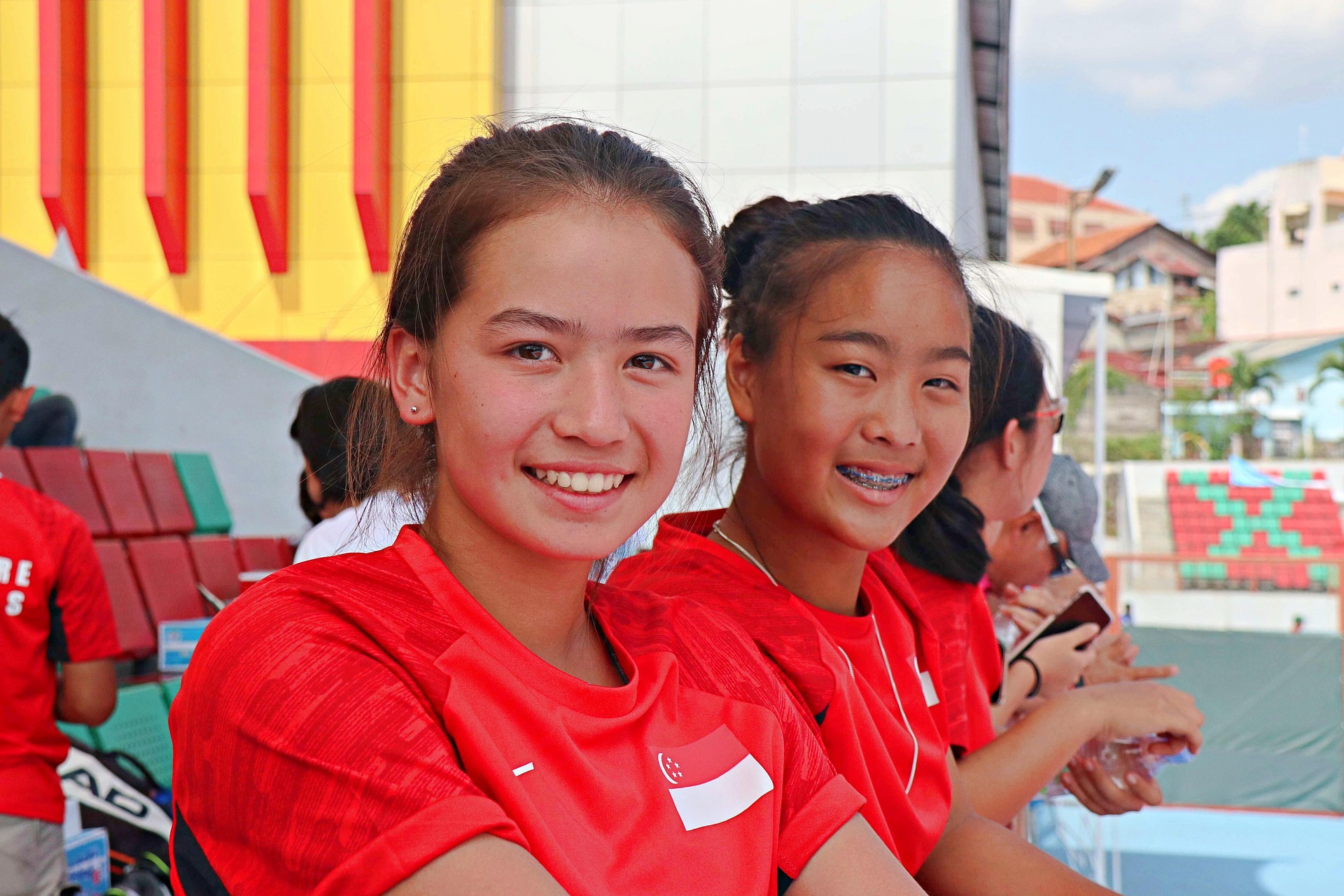 Two disabled school children, in a school playground, smiling to the camera.