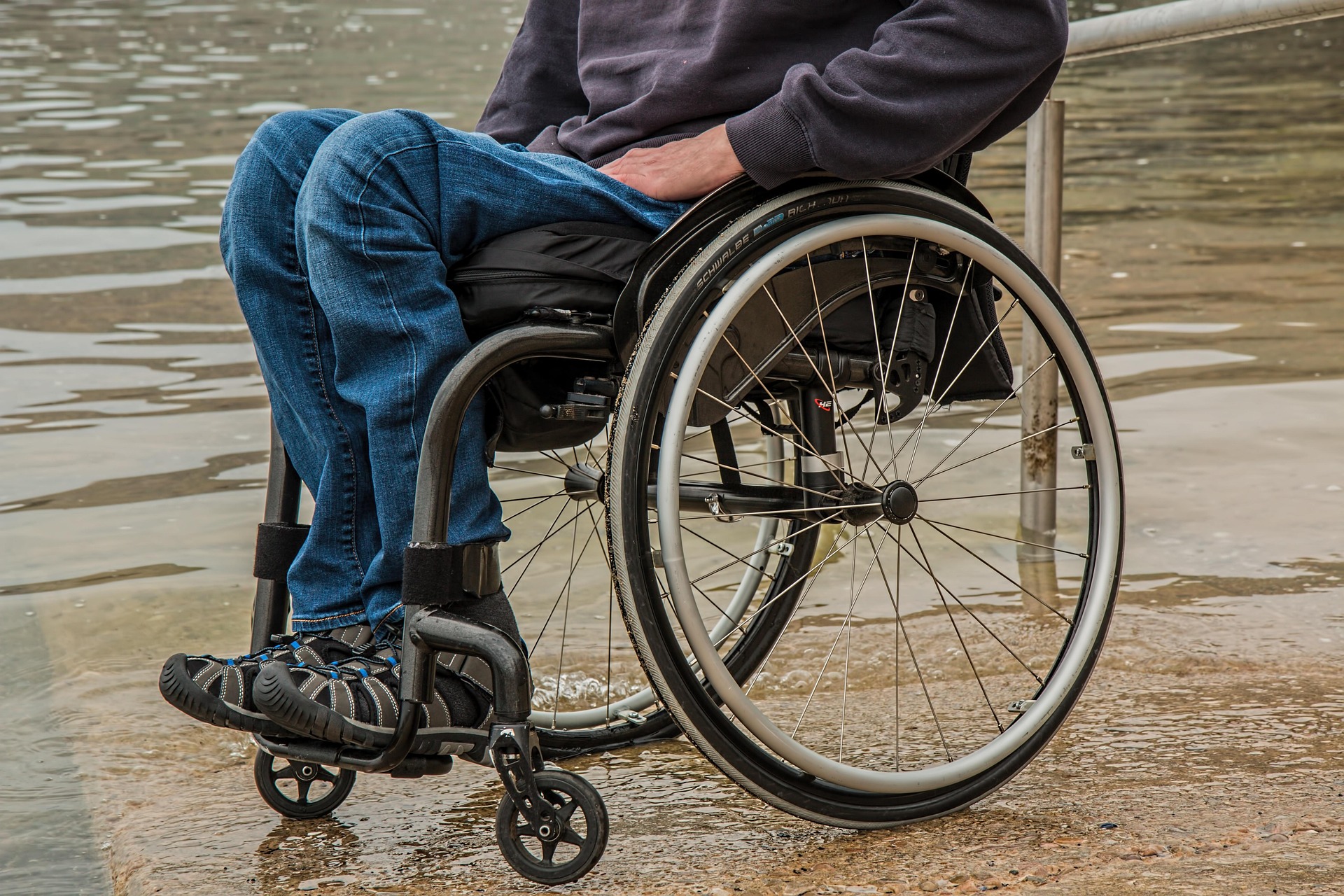 A man on wheelchair strolling along a beach.